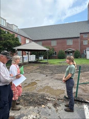 A small group of people gathered outdoors for a community garden discussion at a residential property, emphasizing local gardening and sustainability efforts in Knox County.
