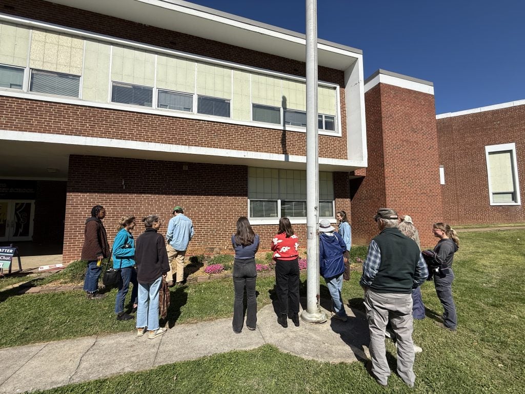 Group of community members gathered outside a modern brick building for the Knox County Community Garden & Growers Alliance meeting.