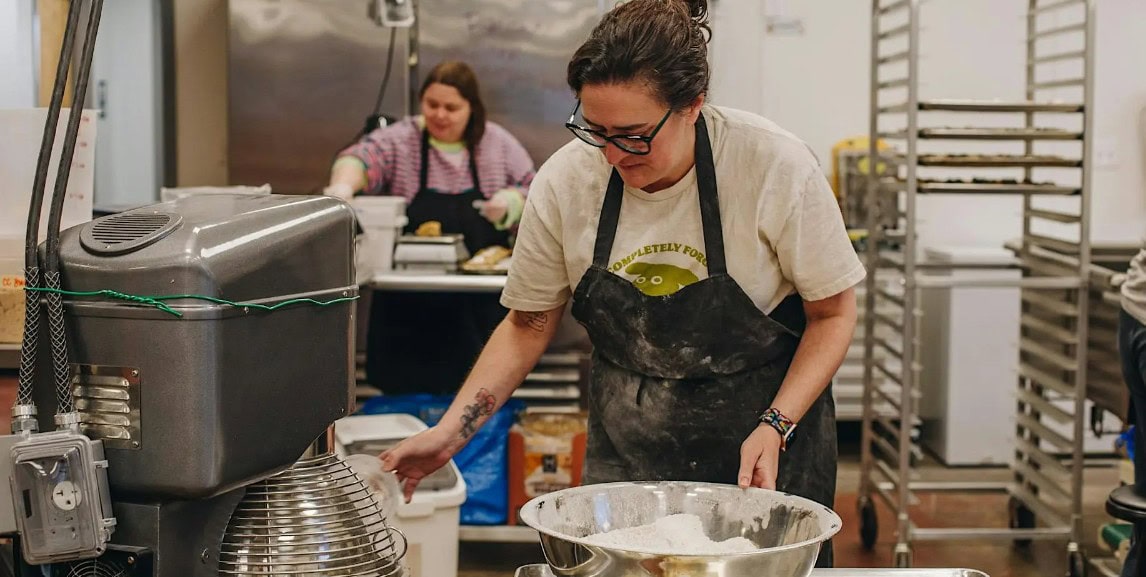 Female chef preparing food in a commercial kitchen.