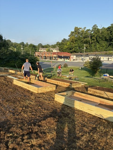 People working together to build raised garden beds at a community garden in Knox County, promoting local food security and community engagement.